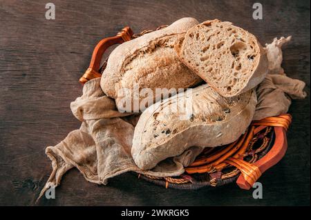 Köstliches frisch gebackenes Sauerteigbrot ohne Hefe auf hölzernem Hintergrund. Hausgemachtes gesundes Brot in einem Korb, Nahaufnahme. Stockfoto