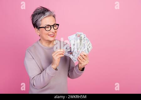 Foto der positiven schönen reichen Frau tragen trendige Kleidung zählt Dollar Geld Geld Kapital isoliert auf rosa Hintergrund Stockfoto