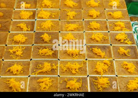 Einheitlich angeordnetes thailändisches Dessert, Mo Kaeng, mit kleinen goldenen Kugeln aus Eigelb und Zucker, auf quadratischem Schliff gesetzt, das den traditionellen AR repräsentiert Stockfoto