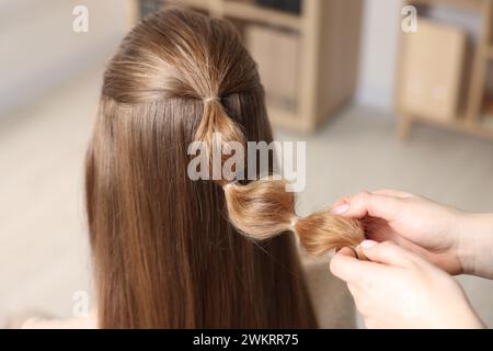 Professionelle Stylistin flechtet die Haare der Frau drinnen, Nahaufnahme Stockfoto