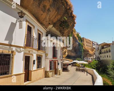 Panoramablick auf Setenil de las Bodegas. Alte weiße Gebäude mit orangefarbenen Ziegeldächern, die in die enge Flussschlucht und in die Felsenüberhänge eingebaut sind. Stockfoto