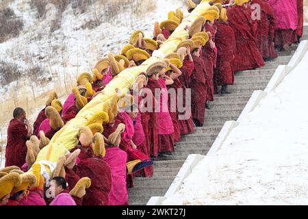 (240222) -- XIAHE, 22. Februar 2024 (Xinhua) -- Mönche tragen ein riesiges Thangka-Gemälde mit dem Bild des Buddha während der jährlichen Zeremonie der 'Sonnensonne des Buddha' des Labrang-Klosters in Xiahe County, nordwestchinesische Provinz Gansu, 22. Februar 2024. Mehr als 40.000 Gläubige und Touristen aus dem in- und Ausland nahmen an einer großen tibetisch-buddhistischen Veranstaltung Teil, bekannt als die Zeremonie der „Sonne des Buddha“, die am Donnerstag im Kloster Labrang in der nordwestchinesischen Provinz Gansu stattfand. Die jährliche Veranstaltung ist eine der wichtigsten Zeremonien im Kloster Labrang, erbaut 1709, einem der sechs großen Tempel Stockfoto