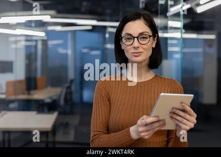 Eine professionelle Frau hält ein Tablet in einer modernen Büroumgebung mit Selbstbewusstsein und Expertise. Stockfoto