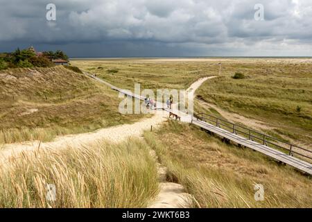 Menschen, die auf einem Fußweg in Dünen in der Nähe des Kniepsand Strandes in Wittdun, Insel Amrum, Nordfriesland, Schleswig-Holstein, Deutschland wandern Stockfoto