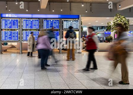 Flughafen Frankfurt - 12. Februar 2024: Menschen in Bewegung verschwimmen beim Gehen vor einer Anzeigetafel für den Abflug Stockfoto