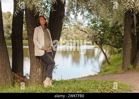 Attraktive schwangere Frau, die im Park im Freien ruht Stockfoto
