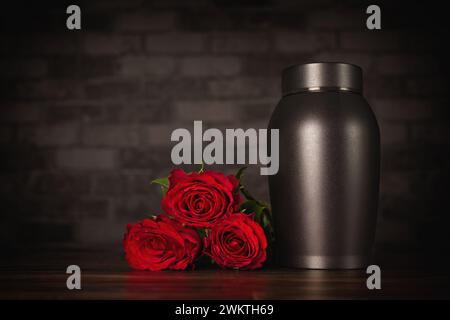 Trauerurne neben einem Haufen Rosen. Stockfoto