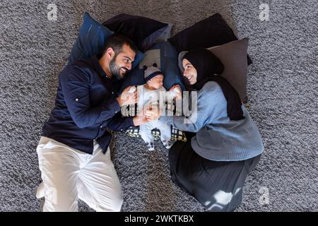 Arabisch-muslimische Eltern teilen einen zärtlichen Moment mit ihrer neugeborenen Tochter und strahlen Liebe und Freude in ihrem Zuhause aus. Stockfoto