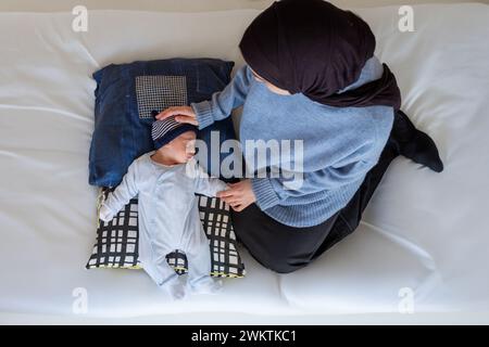 Arabisch-muslimische Eltern teilen einen zärtlichen Moment mit ihrer neugeborenen Tochter und strahlen Liebe und Freude in ihrem Zuhause aus. Stockfoto