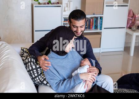 Arabisch-muslimische Eltern teilen einen zärtlichen Moment mit ihrer neugeborenen Tochter und strahlen Liebe und Freude in ihrem Zuhause aus. Stockfoto