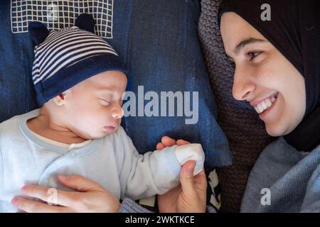 Arabisch-muslimische Eltern teilen einen zärtlichen Moment mit ihrer neugeborenen Tochter und strahlen Liebe und Freude in ihrem Zuhause aus. Stockfoto