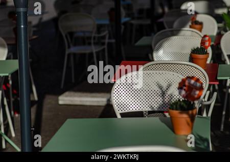 Tische eines Restaurants im Freien auf dem Platz eines Touristenorts, ein weißer Tisch und Stühle, an Feiertagen lieben Touristen, im Sommer draußen zu essen Stockfoto