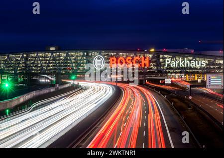 Autobahn A8 am Flughafen Stuttgart mit Bosch-Parkhaus. Die 440 Meter lange Konstruktion bietet 4200 Fahrzeuge Platz. Bosch hat die Namensrechte, der stilisierte Zündanker misst 12 Meter im Durchmesser. Damit ist es eine der größten Leuchtreklamen der Welt. // 04.05.2024: Stuttgart, Baden-Württemberg, Deutschland. *** Autobahn A8 am Flughafen Stuttgart mit Bosch-Parkhaus der 440 Meter lange Baukörper bietet Platz für 4.200 Fahrzeuge Bosch hat die Namensrechte, der stilisierte Zündanker misst 12 Meter Durchmesser und ist damit eines der größten Leuchtschilder der Welt Stockfoto