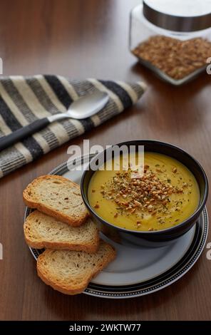 Eine Kürbiscreme mit Knoblauch, serviert mit drei Toaststücken in einer schwarzen Schüssel Stockfoto