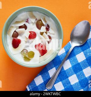 Eine Schüssel Joghurt mit Früchten auf orangefarbenem und kariertem Hintergrund Stockfoto