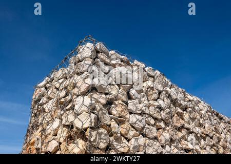 Gabionen-Mauerstein in Metallkäfig vor blauem Himmel Stockfoto