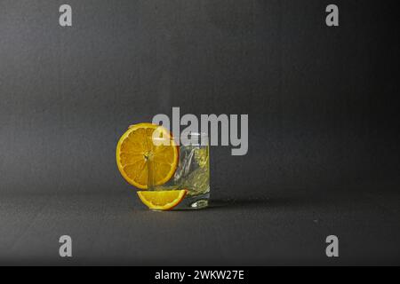 Glasbecher mit wunderbar verschüttetem Saft und Orange auf schwarzem Hintergrund. Stockfoto