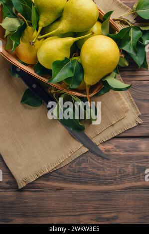 Frische Bio-Birnen mit Blättern. Frische Birnen in der Schale. Auf hölzernem Hintergrund. Frisch reife Birnen.Platz für Text. Draufsicht, flach. Kopierraum. Banner. Stockfoto