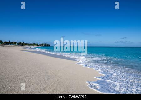 San Salvador Island Bahamas, weißer Sandstrand mit sanft plätscherndem Wasser, fast wolkenloser Himmel, warm und einladend, klares Wasser, friedlich, ideal, Freude Stockfoto