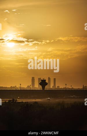 Panoramablick auf das Terminal T4 des Flughafens Madrid Barajas in der Abenddämmerung, mit der Skyline der Stadt und ihren vier Wolkenkratzern im Hintergrund. Stockfoto