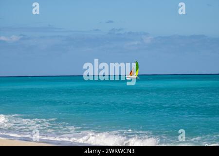 San Salvador Island Bahamas, Katamaran segelt das türkisfarbene Wasser, fast wolkenloser Himmel, bunte Segel, klares, ruhiges Wasser, aufregende Sportarten, Freude Stockfoto