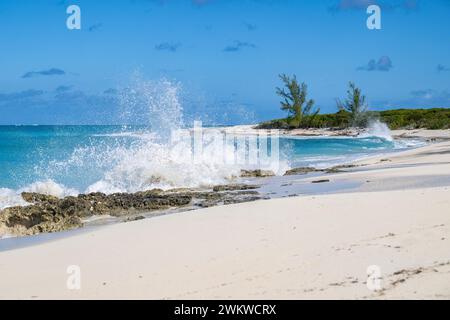 San Salvador Island Bahamas, große Wellen, die auf weißen Sandstrand krachen, fast wolkenloser Himmel, aufregende und wunderschöne Darstellung der Macht des Ozeans Stockfoto