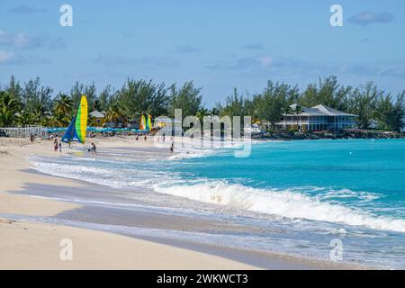 San Salvador Island Bahamas, Menschen spielen am weißen Sandstrand mit Wasser sanft plätschert, fast wolkenloser Himmel, warm und einladend, klares Wasser, Freude Stockfoto