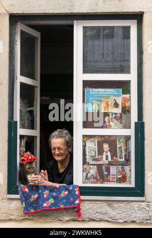 Lissabon, Portugal. 10.05.2023. Eine berühmte ältere Einwohnerin von Lissabon sitzt am Fenster mit ihrer Katze im Hut. Portugal Stockfoto