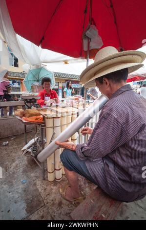 Ein Mann an einem Tabakverkäuferstand in einem chinesischen Markt in Yunnan, der eine traditionelle Pfeife raucht. Stockfoto