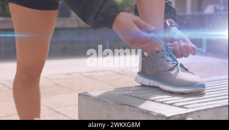 Bild des blauen Lichts, das sich über die Füße einer Frau in Shorts bewegt, die einen Laufschuh bindet Stockfoto