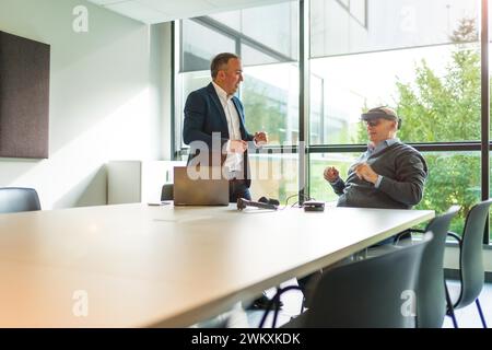 Alte Geschäftsleute, die die imaginäre Welt mit virtueller Realität im Büro reflektieren Stockfoto