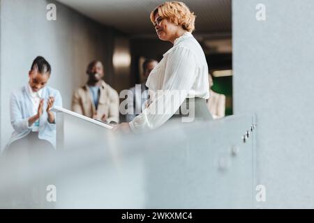 Glückliche Geschäftsfrau, die während eines Seminars von Kollegen Applaus erhält, symbolisiert Anerkennung, Erfolg und berufliche Entwicklung. Youn Stockfoto