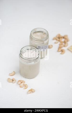 Zwei Joghurts in Glasgläsern mit einem Löffel auf einem Holztisch mit Sonnenlicht, die lange Schatten werfen Stockfoto