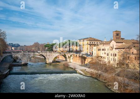 Sonniger Wintertag in Rom mit der kleinen Tiberinsel und Ponte Cestio. Die Szene ist mit einer wunderschönen Brücke und farbenfrohen Gebäuden entlang des Th geschmückt Stockfoto