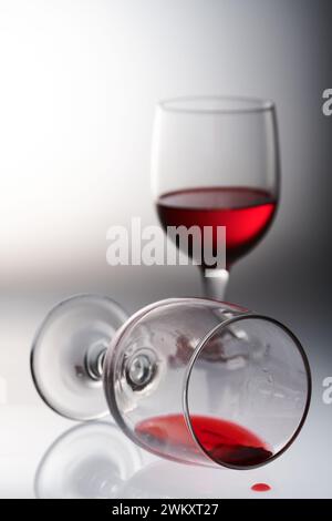 Zwei Gläser Rotwein in verschiedenen Stellungen und auf hellem Hintergrund. Stockfoto