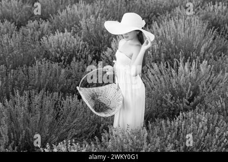 Teenager mit Lavendel auf der Wiese. Teenager-Mädchen mit Lavendelblume, die auf dem Feld steht. Teenager mit Lavendel und Blumenstrauß. Teenager-Mädchen Stockfoto