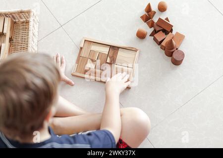 Ein kleines Kind spielt Spielzeug aus Holzbausteinen in einem hellen, minimalistischen Interieur Stockfoto