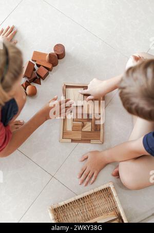 A Tweens, die Holzbausteine spielen, blockieren Spielzeug in einem leichten minimalistischen Innenraum Stockfoto