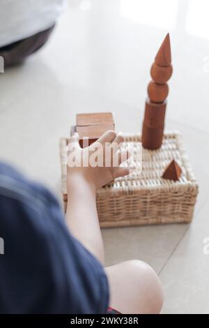 Ein Kind genießt mit einem Korb und Holzblöcken auf dem Boden Stockfoto