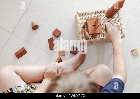 Ein Kind, das mit Spielzeug aus Holzbausteinen in einem hellen, minimalistischen Interieur spielt Stockfoto