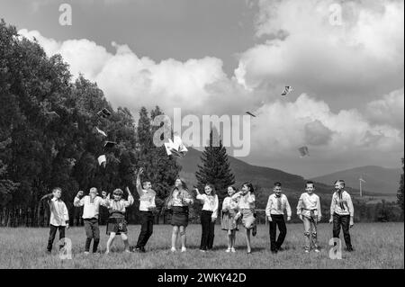 Iwano-Frankiwsk, Ukraine 26. Mai 2023: Eine Gruppe junger Schüler wirft ihre Notizbücher hoch, Berge und Wald im Hintergrund. Stockfoto