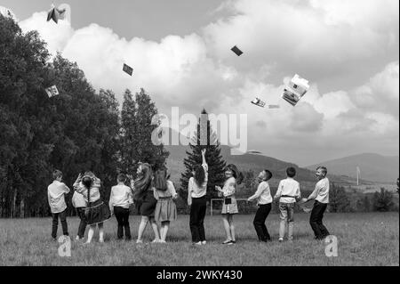 Iwano-Frankiwsk, Ukraine 26. Mai 2023: Eine Gruppe junger Schüler wirft ihre Notizbücher hoch, Berge und Wald im Hintergrund. Stockfoto