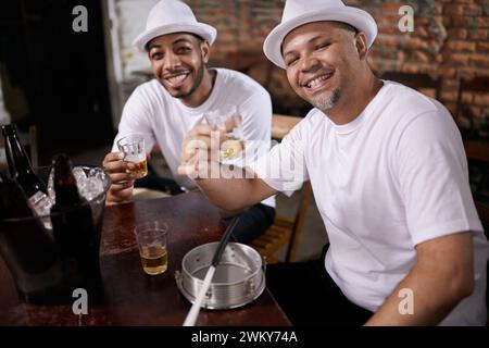 Männer, Freunde und Toast mit Alkohol im Porträt im Pub für viel Glück mit Lächeln, Bonding oder Party mit Bier. Leute, zusammen und glücklich für die Flasche Stockfoto