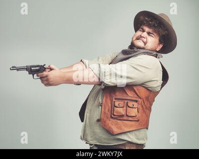 Cowboy, lustiger Mann und Schießpistole im Studio, Waffe und Pistole für den westlichen Kampf isoliert auf weißem Hintergrund. Plus Größe, Kriminelle und Person mit Stockfoto