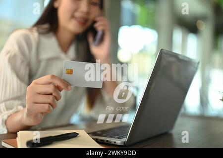 Junge Frau mit Kreditkarte und Eingabe des Verifizierungscodes Login zum Bankkonto auf Laptop Stockfoto