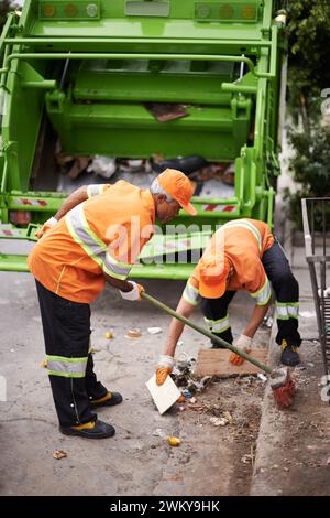 Müllwagen, Besen und Männer mit Abholservice auf der Straße in der Stadt zur Reinigung der öffentlichen Umwelt. Müll, Recycling und männliche Leute, die mit ihnen arbeiten Stockfoto