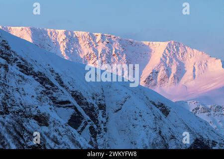 Europa, Norwegen, Troms County, Skjervoy, Mountain Peaks beleuchtet von Dawn Light Stockfoto