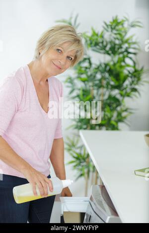 Frau, die zu Hause ein Handtuch in die Waschmaschine lädt Stockfoto