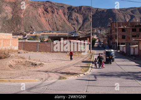 Ein Vater, der sein Kind auf einer Straße in einer Stadt im Heiligen Tal in der Nähe des Inka-Pfads in Peru führt Stockfoto