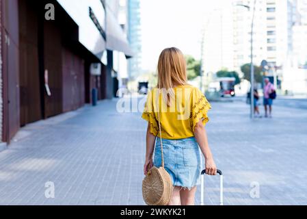 Von hinten gefangen, macht eine junge Frau Schritte auf einer Straße der Stadt Stockfoto